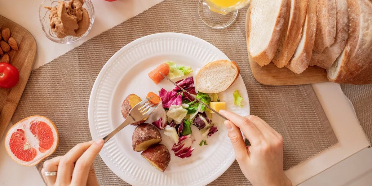Top view of a nutritious breakfast setup with salad, bread, and fresh juice, perfect for a healthy start.