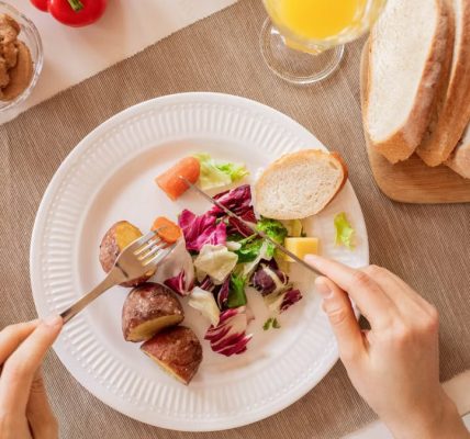 Top view of a nutritious breakfast setup with salad, bread, and fresh juice, perfect for a healthy start.